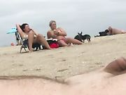 En nudistman sladdar ut vid stranden medan två kvinnor tittar på honom
